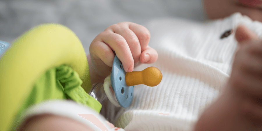 Schnuller in der Hand eines Babies.
