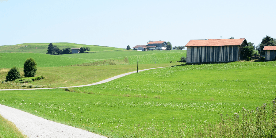Hügelige Landschaft mit wenigen Häusern.