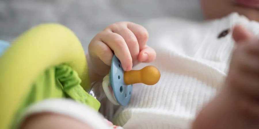 Schnuller in der Hand eines Babies.