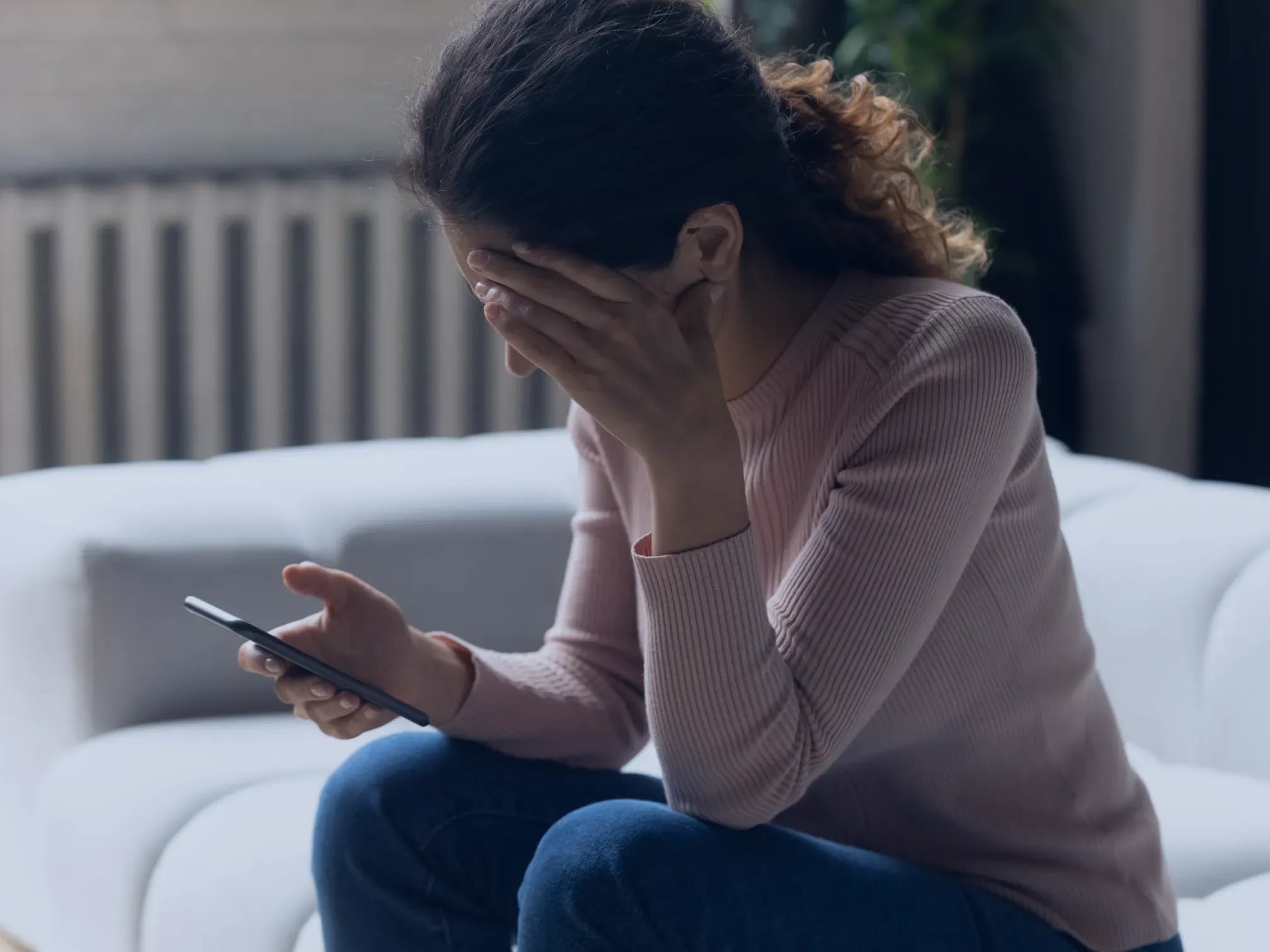 Frau schaut verzweifelt auf Handy