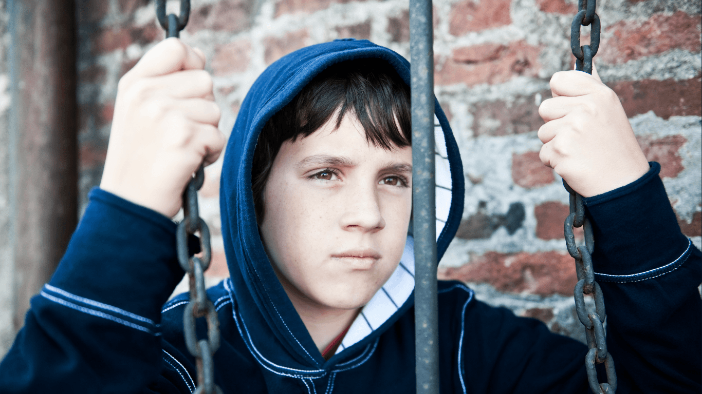 Jugendlicher hinter Eisenstange