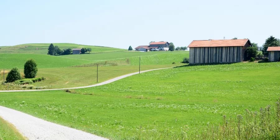 Hügelige Landschaft mit wenigen Häusern.